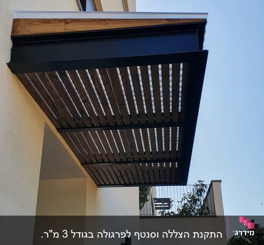 פרגולה מעץ ומתכת מחוברת לקיר חיצוני של בית